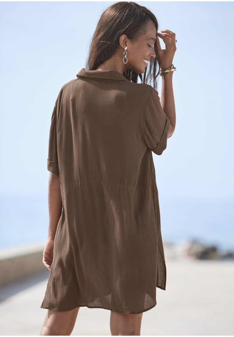 Abito camicia marrone a maniche corte in tessuto leggero e strutturato, dotato di colletto e spacco laterale per facilitare il movimento.