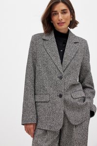 Gray houndstooth blazer with a notched collar, two front pockets, and a single button closure. Material is textured with visible weave details.