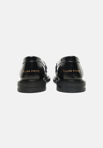 Ζευγάρι μαύρα γυαλιστερά δερμάτινα loafers που φαίνονται από πίσω με το λογότυπο "Filling Pieces" σε χρυσό στην περιοχή της φτέρνας.