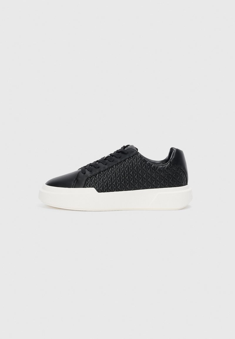Czarne sneakersy z fakturowanym pikowanym wzorem, gładkimi skórzanymi akcentami, płaską białą gumową podeszwą oraz tradycyjnym sznurowaniem.