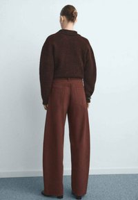 Suéter burdeos extragrande y pantalones de pierna ancha burdeos con acabado texturizado. Diseño simple, vista trasera, sin patrones ni acentos distintivos.