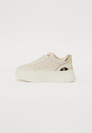 Beige platform teniske z teksturirano zgornjo stranjo, ki ima vzorec z zvezdami, z zlatimi detalji na peti in luknjah za vezalke ter belim gumijastim podplatom.
