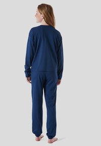 Navy blue long-sleeve shirt and matching pants, made of soft fabric, featuring a relaxed fit and elastic cuffs at the ankles.