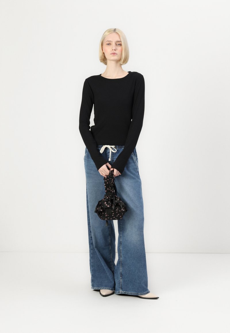 Top nero a maniche lunghe, jeans azzurri a gamba larga con coulisse, tiene una pochette floreale nera. Design minimalista e texture liscia.