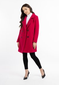 Fuchsia wollen mengsel dubbelzijdig jasje met grote zwarte knopen, ingesneden kraag en zijzakken. Gepaard met zwarte leggings en hakken.