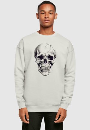 Light grey sweatshirt featuring a detailed black skull graphic on the front. The fabric is soft, with ribbed cuffs and hem.