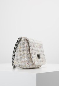 Borsa in tessuto intrecciato bianco con spruzzi multicolori. Presenta una chiusura a pattina e una tracolla in catena metallica. Forma rettangolare.