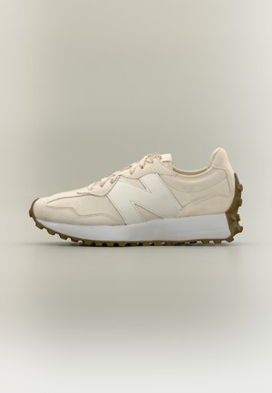 Baskets beige New Balance avec logo blanc "N", semelle marron texturée et semelle intermédiaire blanche, vues de côté sur fond neutre.