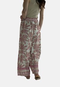 Bloemmotief, wijde broek in het wit met roze en gedempte pastelaccenten. Beschikt over een elastische tailleband en een zachte, lichte stof.