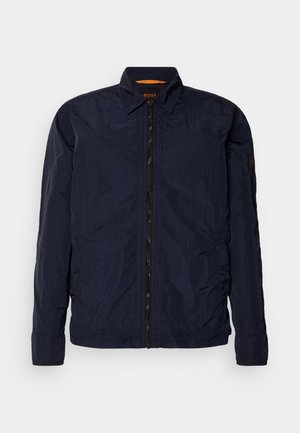 Mornarska lagana jakna s glatkom teksturom, prednjim zatvaračem i ovratnikom. Ima brendiranu unutarnju oznaku i šivane detalje na rukavima.