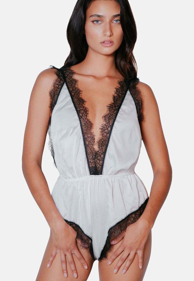 Sidenbodysuit med djup V-ringning och svart spetskant. Har satintyg, volangkanter och elastisk midja för en bra passform.