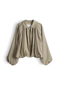 Blouse beige à manches longues avec manches bouffantes et fermeture éclair sur le devant, avec un col classique et un ourlet ample et froncé.