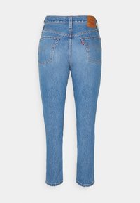 Light blue denim jeans with a tapered leg, featuring two back pockets and a brown leather patch on the waistband.