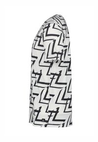 Camiseta de manga corta en blanco con un patrón abstracto de zigzag negro. Presenta un escote redondo y un ajuste estándar. El material tiene una textura suave.