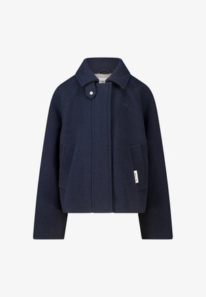 Veste en laine bleu marine avec col, patte de cou boutonnée, deux poches avant et une petite étiquette blanche de marque sur la poche droite.