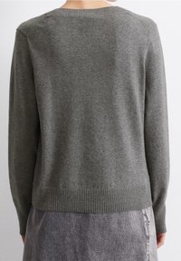 Harmaa neulepaita pyöreällä kaula-aukolla, ribbaustaskulla ja hihan suilla. Kangas näyttää pehmeältä hienovaraisella tekstuurilla, esitetty takaa.