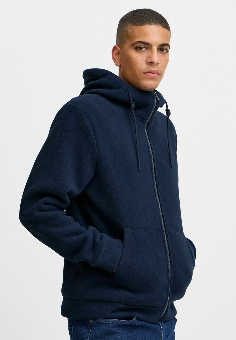 Marine blauwe fleece zip-up hoodie met een hoge kraag, trekkoord en voorzakken. Gladde textuur, relaxte pasvorm en casual ontwerp.