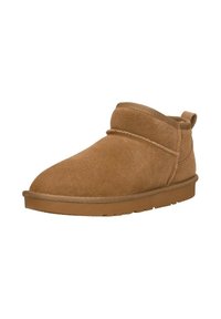 Tan nubuck enkellaarsjes met een afgeronde neus, minimale stiksels en een lipje aan de achterkant. Platte rubberen zool voor stabiliteit en comfort.