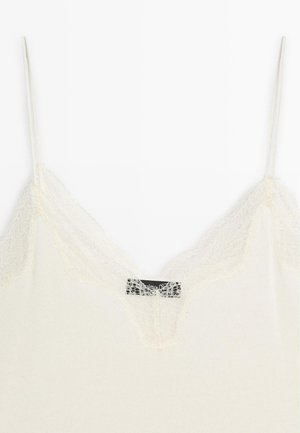 Weißes Trägershirt mit Spitzenbesatz am Halsausschnitt, dünne Träger und eine weiche, gerippte Textur. Etikett innen sichtbar.