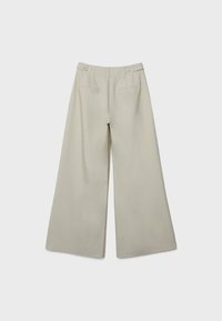 Pantalon beige à jambes larges avec détails de boutons sur le côté et poches arrière passepoilées, présenté à plat sur un fond clair.