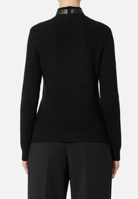 Maglione nero lavorato a maglia con maniche lunghe, texture a coste e collo alto. Presenta un dettaglio in pelle sul collo.