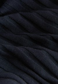 Gestructureerde, donkerblauwe stof met zichtbare ribpatronen, die diepte en dimensie creëren. De zachte en flexibele uitstraling doet denken aan breimateriaal.