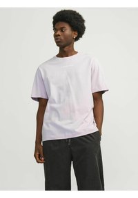 T-shirt a maniche corte color lavanda chiaro con testo "FUTURE EDTN" in bianco, abbinato a pantaloni corti scuri con dettagli laterali. Tessuto in cotone, vestibilità rilassata.