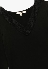 Zwarte lange mouw top met een V-hals en kantafwerking, gemaakt van zachte stof. Label zichtbaar aan de binnenkant van de kraag met de tekst "Koton," maat S.