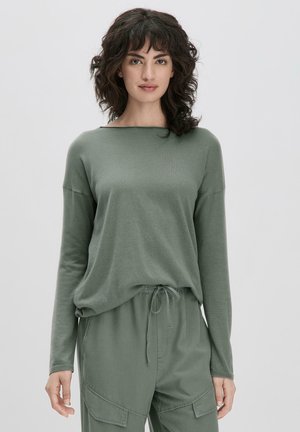 Top verde de manga larga hecho de una tela suave con un corte relajado, que presenta un escote ancho y costuras de hombro caídas.