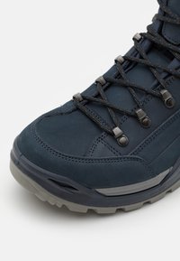 Herenwandelschoen gemaakt van marineblauw leer met een gestructureerd oppervlak, versterkte neus, metalen oogjes en een grijze rubberen zool met profielpatronen.