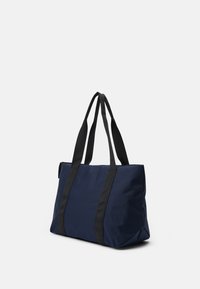 Sac en toile en tissu bleu marine avec des poignées en toile noires, de forme rectangulaire et au design minimaliste. Matériau durable avec une texture lisse.