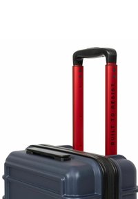 Tvrdý kufr v námořnické modři s texturovaným povrchem, černým zipem a červenou teleskopickou rukojetí označenou "BUILT TO RESIST". Lehké a odolné provedení.