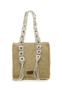 Bolso de paja trenzada con asas de macramé en crema, que presenta nudos decorativos y borlas, y una pequeña etiqueta de logo marrón en la parte delantera.