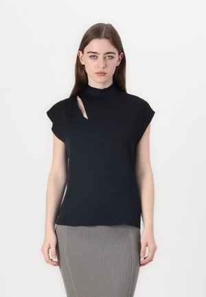 Svart topp med høy hals og asymmetrisk utskjæringsdetalj, med capsleeves og en glatt, elastisk tekstur. Kombinert med et ribbestrikket skjørt.