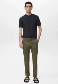Dark gray short-sleeve shirt paired with slim-fit olive green pants and black sandals. The outfit features a simple, modern design.