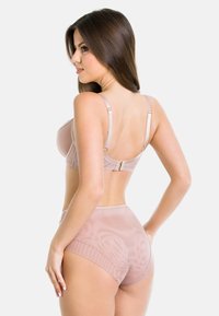 Beżowy biustonosz z regulowanymi ramiączkami, z fiszbinami i zapięciem na haftkę. Pasuje do wysokich majtek w podobnym odcieniu i przezroczystej strukturze.