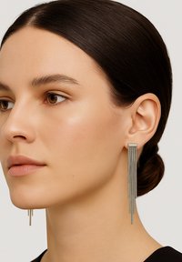 Lange Ohrringe in Silberton mit linearer Fransenoptik in unterschiedlichen Längen, die eine elegante, metallische Textur zur Schau stellen.