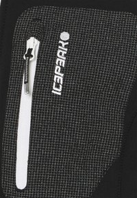 Tela de chaqueta negra y gris con un patrón texturizado, que presenta un bolsillo con cremallera blanca y un logo bordado.