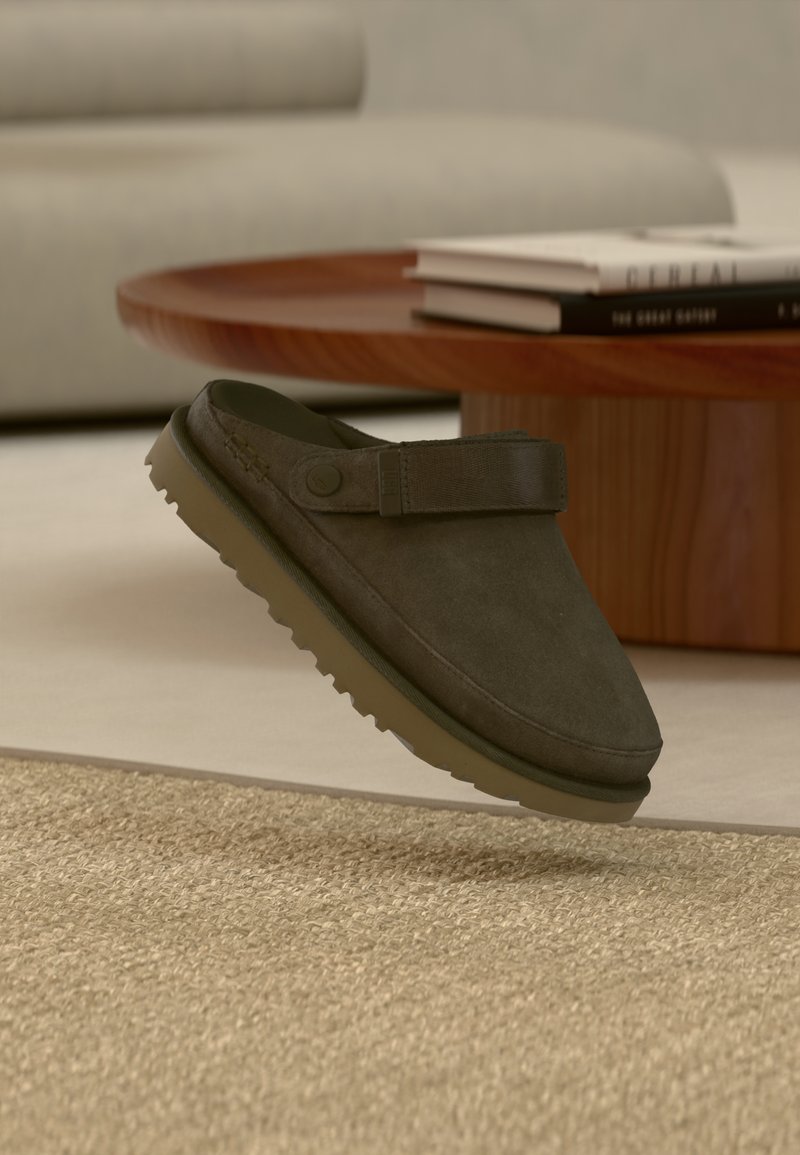 Chaussure en daim vert foncé à enfiler avec une tige texturée et une bride sur le cou-de-pied, équipée d'une semelle en caoutchouc à motif multidirectionnel.