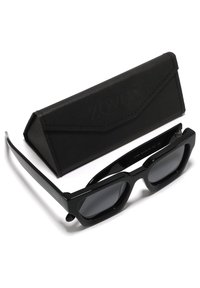 Occhiali da sole neri a forma rettangolare con lenti scure, caratterizzati da montature spesse e una finitura opaca. Include una custodia nera coordinata con logo.