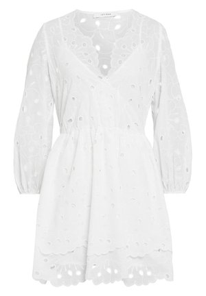 Robe blanche avec de longues manches bouffantes, ornée de broderies florales et de découpes. Taille élastique avec une jupe évasée et un ourlet à volants.