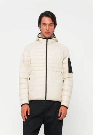 Puffer jacket in light beige with black zippers and accents. Features a hood, vertical seams, and zippered pockets on the front.