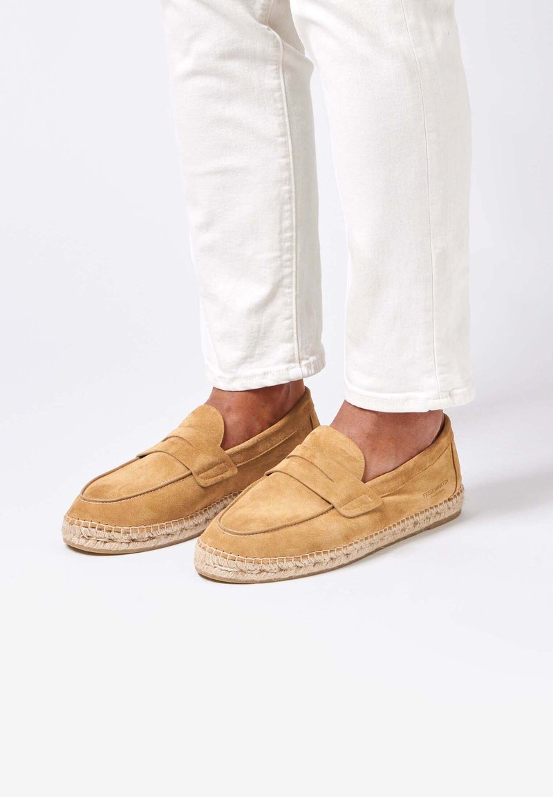 Mocassins en daim beige avec un design de style mocassin et des détails en couture, dotés d'une semelle en corde de jute pour une texture et un contraste.
