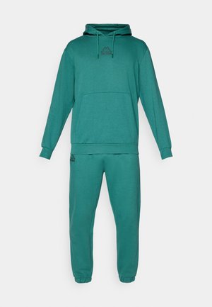 Tealfärgad hoodie och sweatpants-set, tillverkat av mjukt tyg. Hoodien har en känguruficka, dragsko i huvan och logotypdetalj på bröstet.