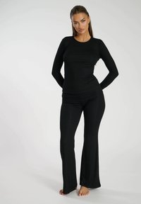 Czarny zestaw składający się z długiego rękawa i spodni w kształcie dzwonów, wykonany z elastycznego prążkowanego materiału, z dopasowanym krojem i gładką teksturą, bez widocznych wzorów.