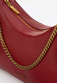 Bolso de mano de cuero rojo con una superficie texturizada, correa de cadena dorada y un cierre visible con una etiqueta de marca.