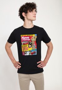 Svart t-shirt med en färgglad grafisk tryck som liknar ett tidningsomslag, med text och bilder relaterade till korvar och humor.