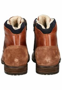 Botas de tobillo de cuero marrón y gamuza con forro de piel de oveja, cierre de cremallera y acentos texturizados. Punta redondeada y suela de goma.