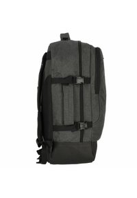 Mochila de tela gris con acabado texturizado, presenta una base de cuero negro, correas de compresión laterales ajustables y un asa superior.