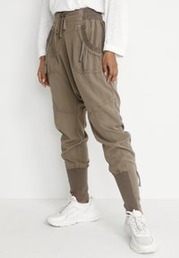 Kaki cargobyxor med dragsko i midjan, flera fickor, ribbade mudd och texturerad tyg. Stylade med vita sneakers.